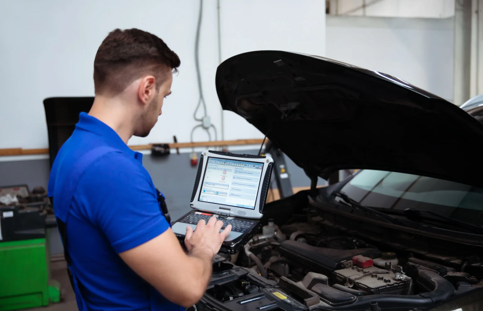 jeune-mecanicien-automobile-confiant-et-beau-avec-un-ordinateur-portable-a-la-main-effectue-des-diagnostics-informatiques-pour-les-erreurs-dans-les-systemes-de-la-voiture (1)